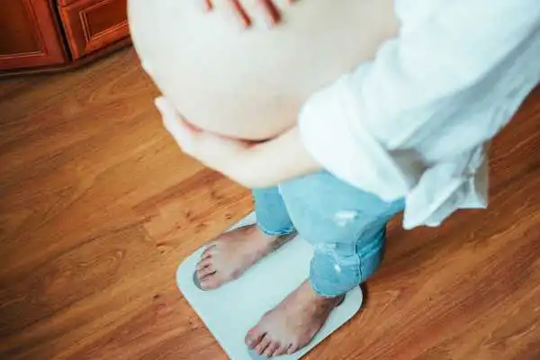 Image of woman weighing herself and experiencing weight gain through pregnancy Isle of Isla